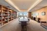 Built-in floor-to-ceiling shelving, recessed ceiling lighting, wood paneling, and expansive windows