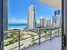 Balcony with glass panel railings, wood-finish flooring, and coastal scenery