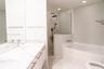 Dual-sink vanity with stone-finish countertop, walk-in shower with glass enclosure and rainfall showerhead, and a deep soaking tub with wall-mounted c