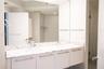Double-sink vanity featuring stone countertops, white flat-panel cabinetry, modern hardware, and a wall-to-wall mirror