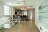 Open-concept interior featuring light wood-finish flooring, a contemporary island kitchen, built-in frosted glass shelving, and a decorative drop-pend