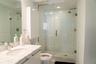 Bathroom featuring a stone-top vanity with an undermount sink, glass-enclosed shower with tile surround, and recessed lighting