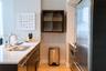 Kitchen featuring flat-panel dark cabinetry, white countertops, integrated stainless steel refrigerator, undermount double-basin sink with a gooseneck