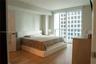 Floor-to-ceiling windows with integrated glass balcony railing, wood-finish flooring, and neutral wall tones