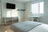 Light-filled room featuring wood-finish flooring, a large window with roller shade, and a wall-mounted floating shelf