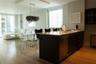 Kitchen island with stone-surface countertop, stainless steel undermount sink, flat-panel dark cabinetry, and wood-finish flooring