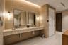 Floating vanity with a speckled countertop, dual rectangular sinks, recessed LED accent lighting, textured wall detailing, and sleek, minimalist wall-