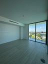 Floor-to-ceiling windows, wood-finish flooring, and access to a glass-railed balcony with a landscape backdrop