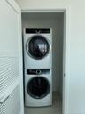 Stacked washer and dryer unit concealed by louvered closet doors