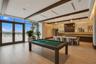 Expansive interior space featuring plank-style tile flooring, exposed wood-beam ceiling, built-in cabinetry with tiled backsplash, and floor-to-ceilin