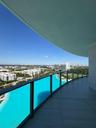Curved balcony featuring large-format tile flooring and a glass panel railing with a dark metal frame