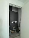 Dedicated utility closet housing a vertical HVAC air handler unit with integrated plumbing and gas line connections