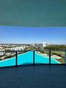 Covered balcony featuring large-format tile flooring and a glass railing