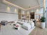 High ceilings with integrated cove lighting, recessed ceiling accents, built-in recessed wall shelving with stone-finish backings, and wood-finish flo