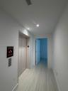Hallway featuring recessed ceiling lighting, smooth-finish walls, and light-toned stone-finish flooring with integrated elevator access