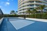 Outdoor pickleball court featuring a multi-toned blue modular surface, perimeter chain-link fencing, and white masonry boundary walls