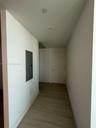 Hallway featuring wood-finish flooring, recessed ceiling lighting, and a flush-mounted solid-core door