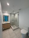 Bathroom featuring a wood-finish vanity with a rectangular undermount sink, a frameless glass-enclosed shower with floor-to-ceiling tile surround, and