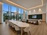 Double-height floor-to-ceiling windows, wood-finish flooring, recessed tray ceiling with integrated lighting, custom fluted millwork, and a textured w