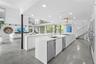 Double-height living area with floor-to-ceiling glass walls, polished concrete flooring, open-concept kitchen with built-in cabinetry, and wood-finish