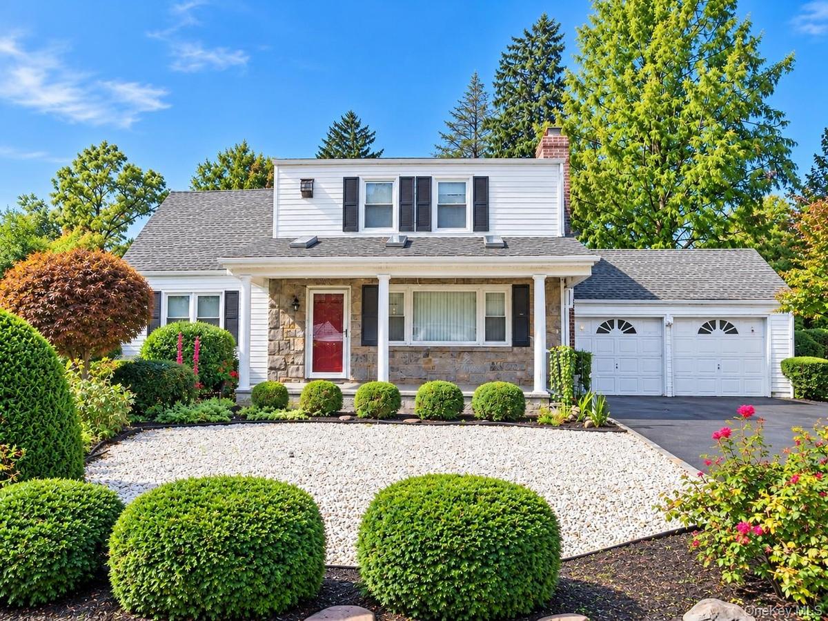 White siding exterior with a stone facade, a covered Porch entry with columns, a two-car garage, and a Driveway that can accommodate 4 or more vehicle