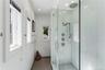 Walk-in shower featuring glass paneling, white subway tile surround, rainfall showerhead, handheld shower sprayer, and stone tile flooring