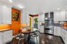Kitchen featuring white cabinetry, stainless steel gas range with professional-style hood, dark mosaic tile backsplash, and dark tile flooring