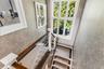 Staircase featuring glass panel railings, wood handrails, patterned wall covering, and a multi-pane window