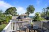 Elevated deck featuring white railing and lattice screen, overlooking mature trees and coastal scenery