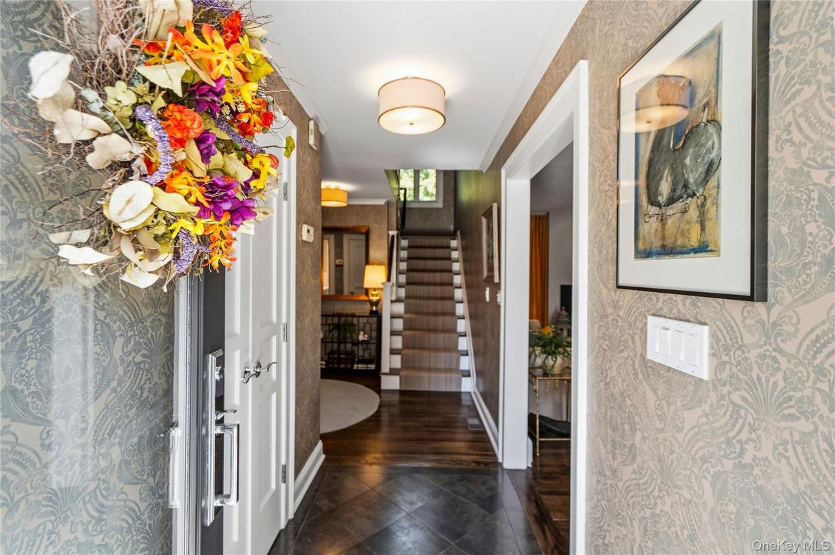Foyer featuring damask-patterned wallpaper, dark-toned stone floor tile, wood-finish flooring, and recessed ceiling lighting