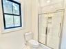 Bathroom featuring a shower stall and baseboards
