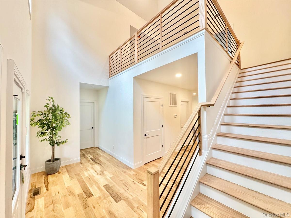 Stairway with a high ceiling, wood finished floors, and recessed lighting