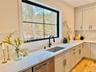 Kitchen with stainless steel dishwasher, light stone counters, tasteful backsplash, and light wood-style flooring