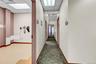 Hallway featuring dark colored carpet and a paneled ceiling