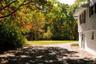 Exterior siding, gravel driveway, and expansive lawn bordered by mature trees