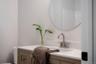 Bathroom vanity featuring a wood-finish cabinet, stone-patterned countertop with an integrated basin, brushed-nickel faucet, and a circular wall-mount