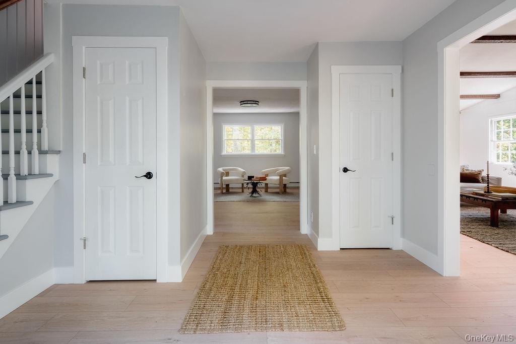 Foyer featuring wood-finish flooring, white paneled interior doors with matte black hardware, and a staircase with white balusters