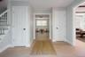 Foyer featuring wood-finish flooring, white paneled interior doors with matte black hardware, and a staircase with white balusters