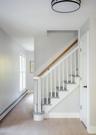 Staircase featuring a natural wood handrail, white painted spindles, and grey-toned treads, complemented by wide-plank wood-finish flooring and a circ