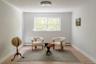 Interior room featuring wood-finish flooring, diagonal-patterned millwork, a double-hung window, and a central flush-mount ceiling fixture