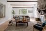 Living area featuring wood-finish flooring, exposed ceiling beams, and a floor-to-ceiling stone fireplace with a stone hearth