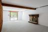 Interior space featuring a brick fireplace with a wood mantel, exposed structural wood beam, painted masonry walls, recessed lighting, and a sliding g