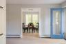 Light-toned wood-finish flooring, white shaker-style cabinetry, and a blue-painted door featuring a full-length glass pane