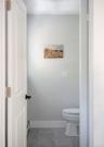 Neutral-toned walls, gray tile flooring, and a white porcelain toilet