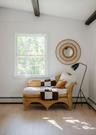 Vertical wood-paneled walls, exposed ceiling beams, light-tone wood-finish flooring, and a single-hung window with a grid pattern