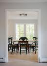 Interior space featuring clean white trim, light wood-finish flooring, dual windows with exterior foliage, and a geometric flush-mount ceiling light f
