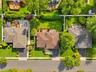 Aerial perspective of the property featuring a rear wood deck, manicured lawn, established landscaping, and a fenced perimeter