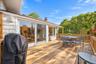 Expansive wood deck with a perimeter railing, light-toned shingle siding, and floor-to-ceiling sliding glass doors