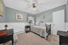 Room featuring beadboard wainscoting, neutral wall paint, carpeting, and a ceiling fan with integrated lighting
