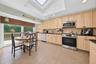 Kitchen featuring light wood cabinetry, stone countertops, stainless steel appliances, a skylight, and tile flooring